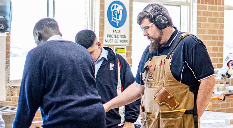 Two students and an educator engaged in a woodworking class at Emmaus Catholic College Kemps Creek