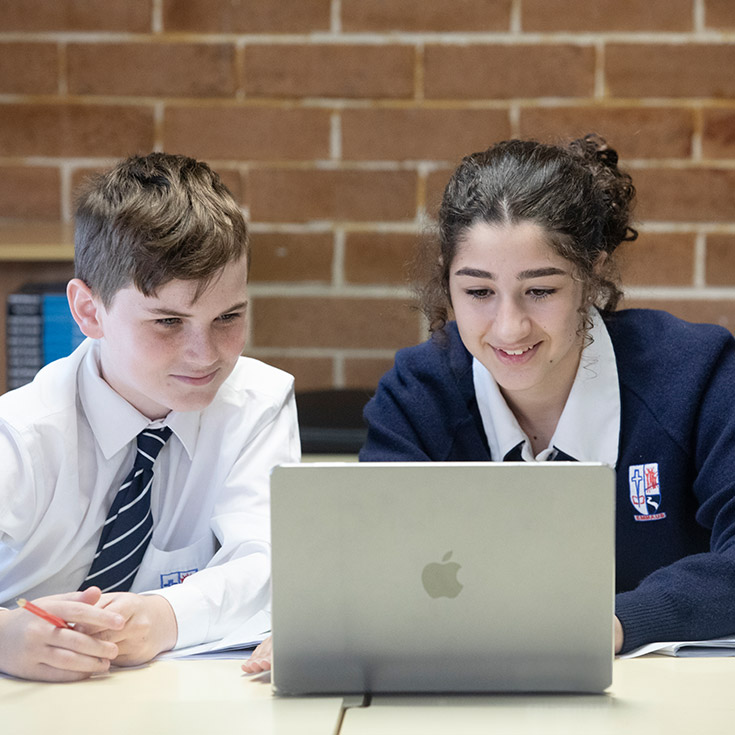 Two Emmaus Catholic College students studying off of a laptop